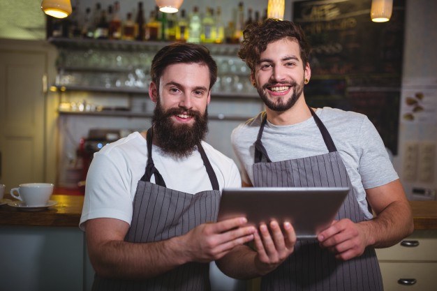 smiling-waiter-using-digital-tablet-counter-cafa-c_1170-625